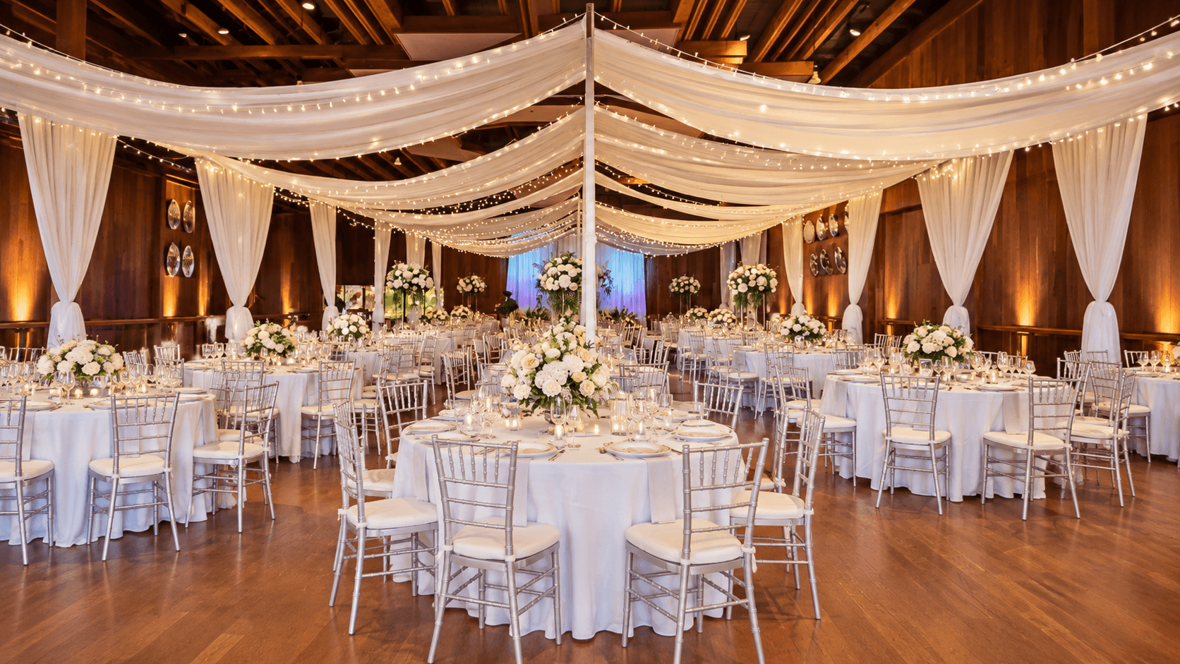 Elegant reception with draped ceiling, tables, chairs, and floral centerpieces